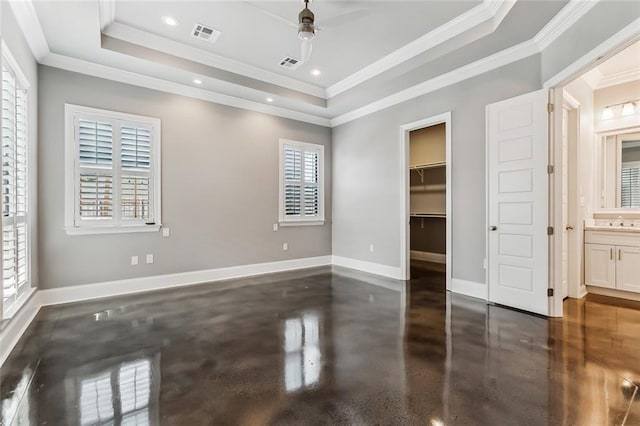 unfurnished bedroom featuring ceiling fan, multiple windows, a tray ceiling, and ornamental molding