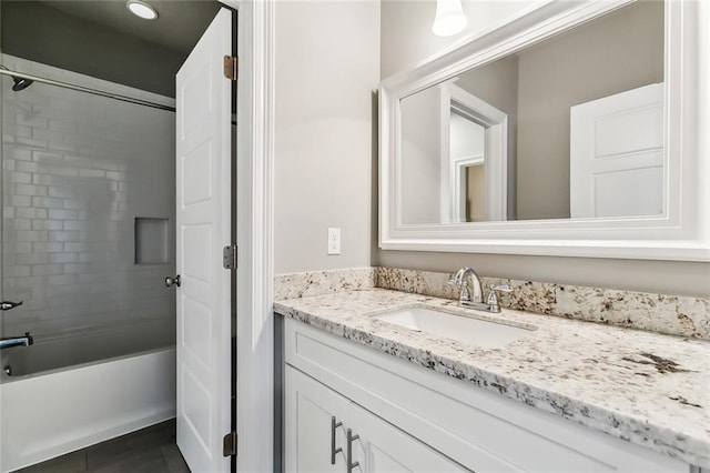 bathroom with tile patterned flooring, tiled shower / bath, and vanity