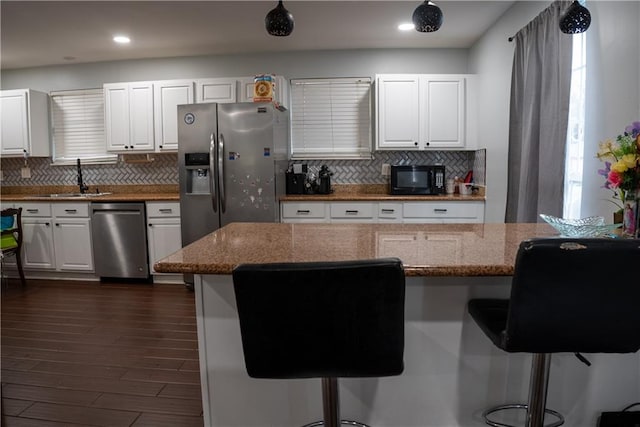 kitchen featuring a kitchen breakfast bar, white cabinetry, stainless steel appliances, and tasteful backsplash