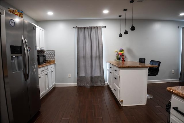 kitchen with decorative light fixtures, white cabinetry, stainless steel fridge with ice dispenser, and kitchen peninsula