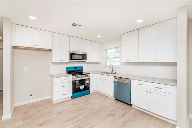 kitchen featuring appliances with stainless steel finishes, light hardwood / wood-style flooring, white cabinetry, and sink