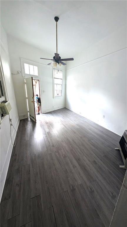 unfurnished living room with ceiling fan and dark wood-type flooring