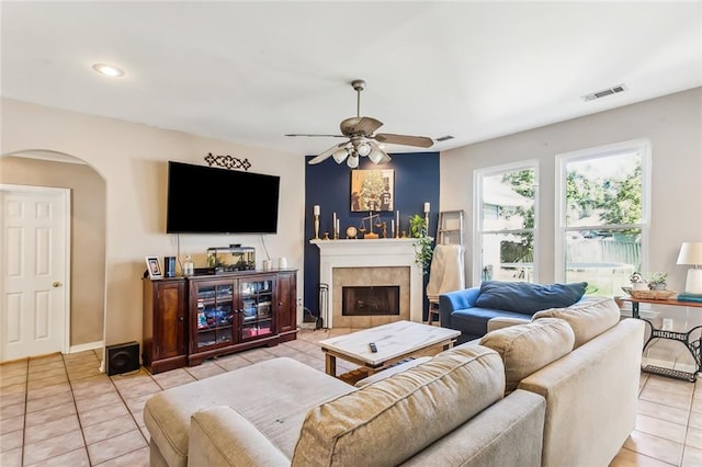 tiled living room featuring ceiling fan and a fireplace