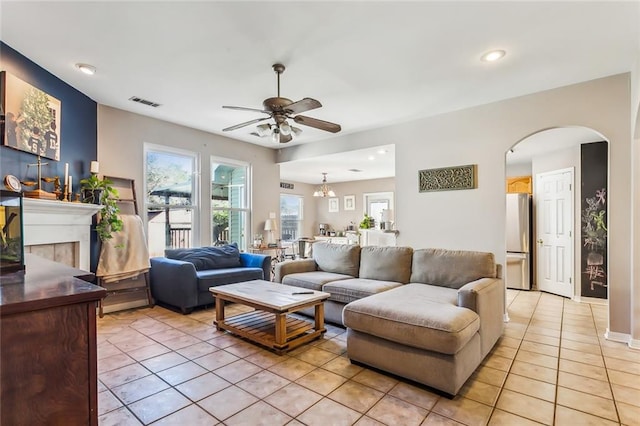 tiled living room with ceiling fan and a fireplace