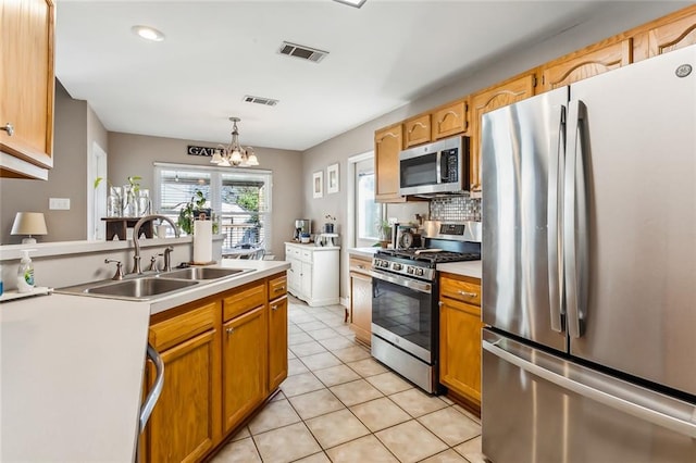 kitchen featuring sink, hanging light fixtures, light tile patterned floors, a notable chandelier, and stainless steel appliances