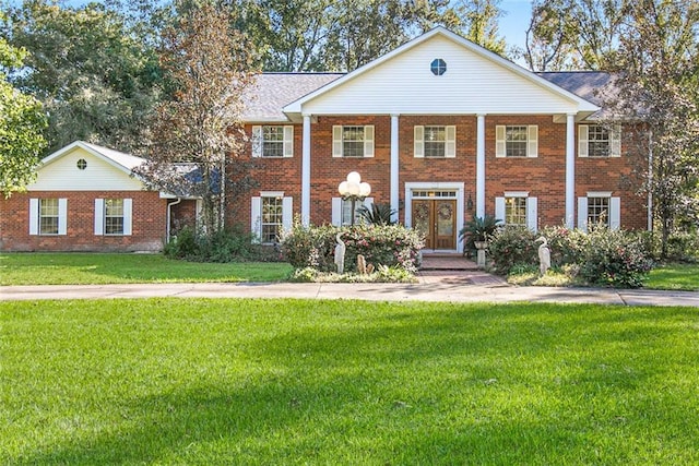 neoclassical home featuring brick siding and a front yard