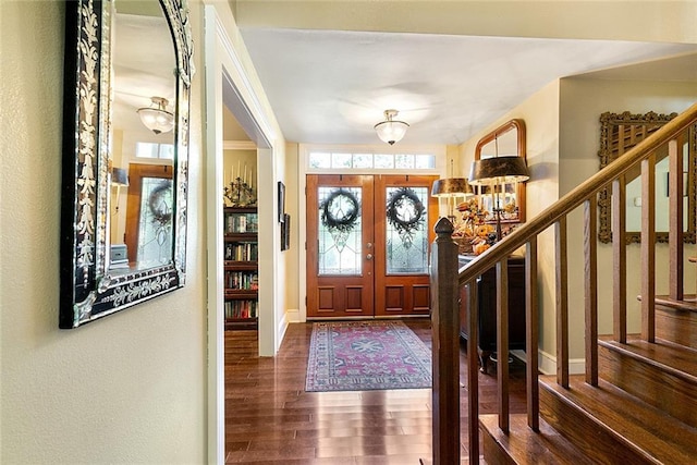 entrance foyer featuring wood finished floors, baseboards, french doors, and stairs