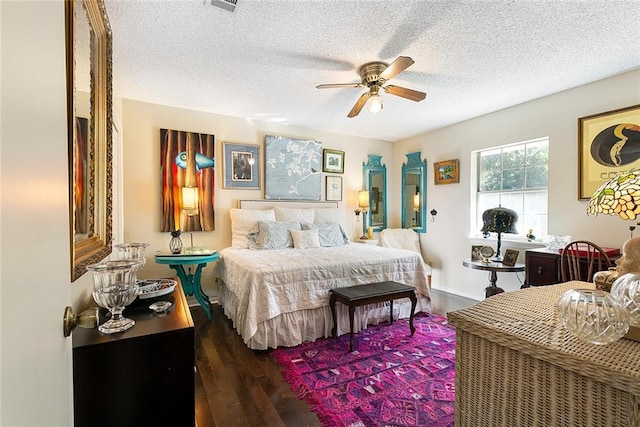 bedroom with dark wood-style floors, visible vents, a ceiling fan, and a textured ceiling