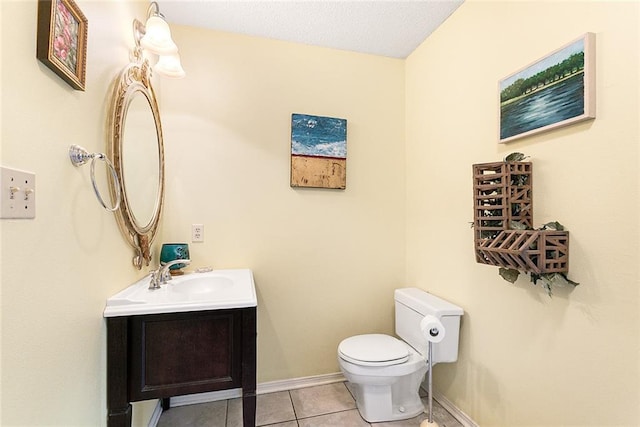 half bathroom with toilet, baseboards, vanity, and tile patterned floors