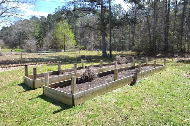 view of yard featuring a garden, fence, and a wooded view