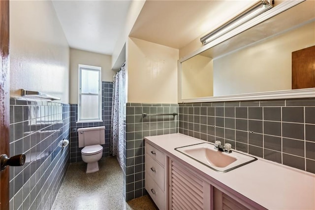 bathroom featuring vanity, toilet, and tile walls