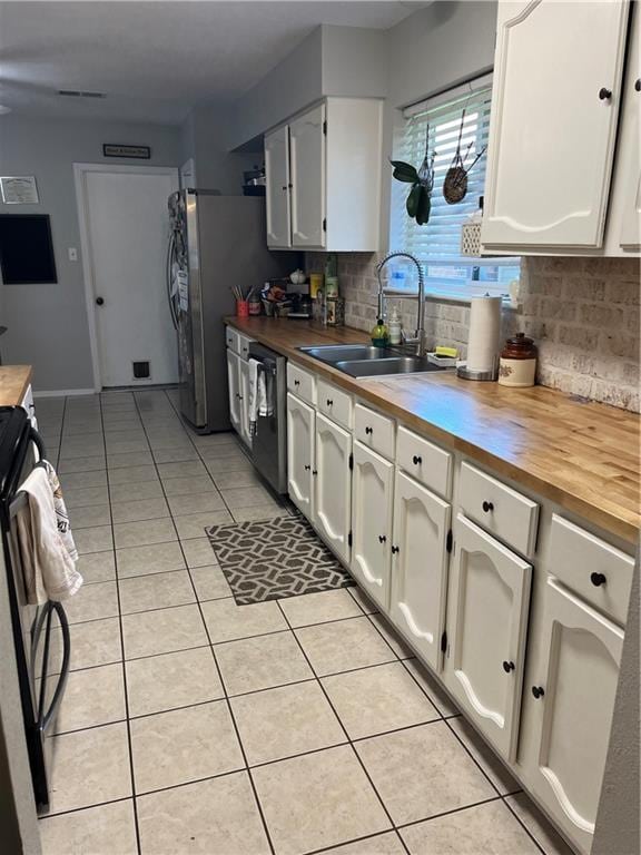 kitchen featuring butcher block countertops, dishwasher, stove, and white cabinets