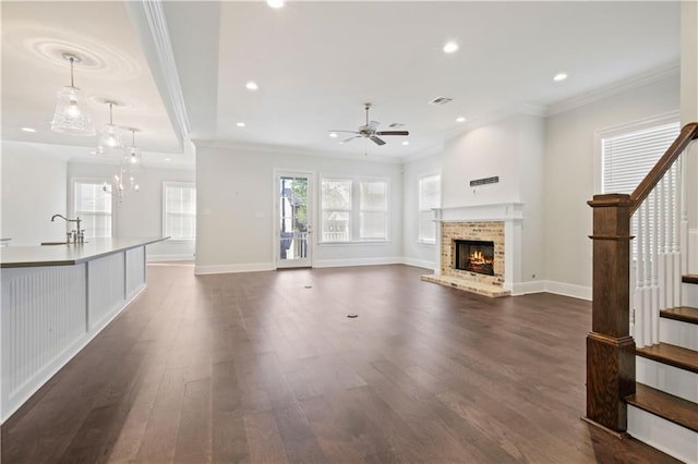 unfurnished living room featuring dark hardwood / wood-style flooring, ceiling fan, sink, and a brick fireplace