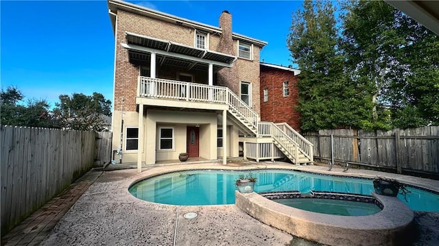 back of house with a pool with hot tub