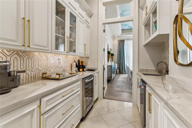 kitchen featuring sink, wine cooler, light tile patterned floors, light stone counters, and white cabinetry