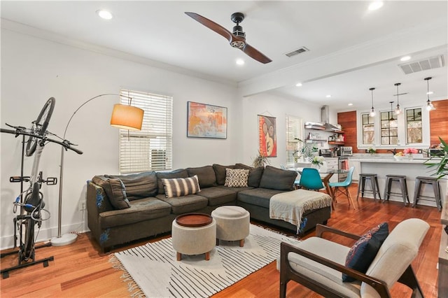 living room featuring crown molding, ceiling fan, and light wood-type flooring