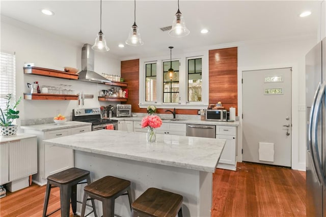 kitchen featuring pendant lighting, white cabinets, wall chimney range hood, dark hardwood / wood-style floors, and stainless steel appliances