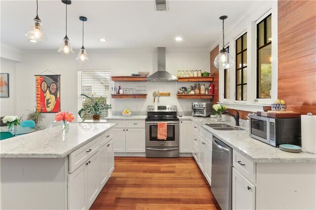 kitchen featuring wall chimney range hood, sink, light hardwood / wood-style floors, white cabinetry, and stainless steel appliances