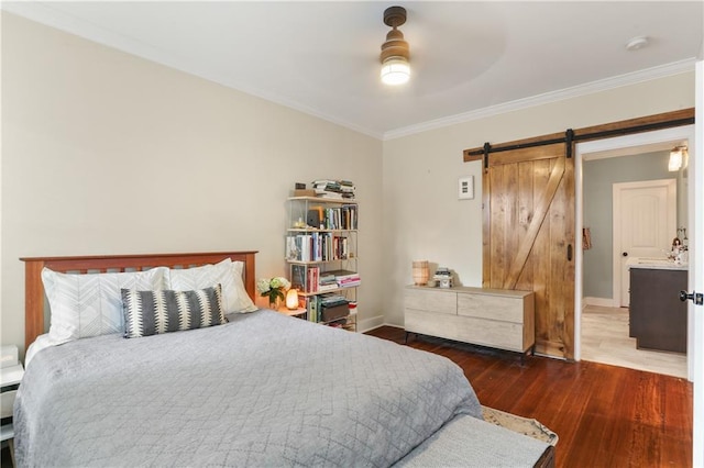 bedroom featuring ensuite bath, ceiling fan, a barn door, dark hardwood / wood-style floors, and ornamental molding