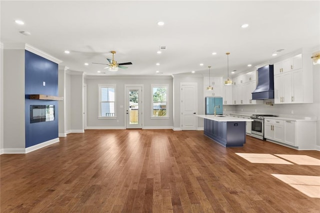 kitchen with stainless steel gas range oven, white cabinets, hanging light fixtures, dark hardwood / wood-style floors, and custom range hood