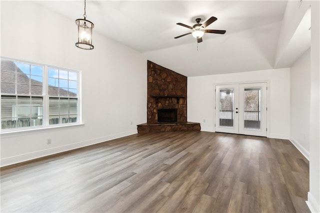 unfurnished living room with french doors, wood-type flooring, high vaulted ceiling, a fireplace, and ceiling fan with notable chandelier