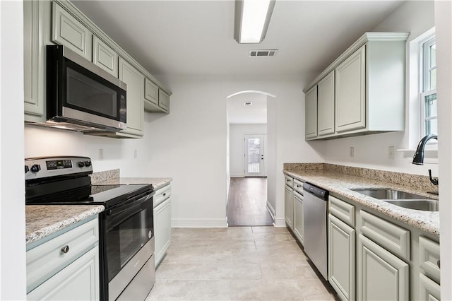 kitchen featuring sink, light tile patterned flooring, stainless steel appliances, and light stone countertops