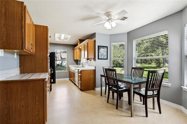 kitchen featuring black refrigerator, a textured ceiling, white dishwasher, ceiling fan, and sink