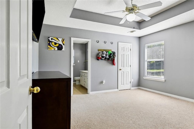 bedroom with ceiling fan, light carpet, and ensuite bath