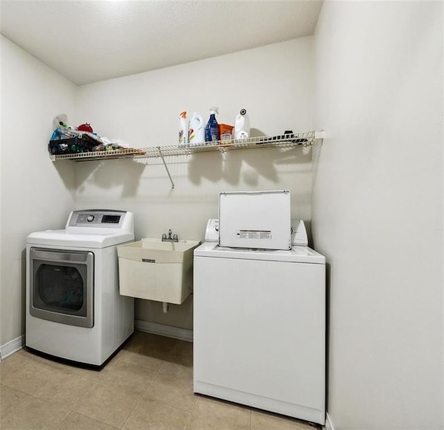 clothes washing area featuring light tile patterned flooring, sink, and washing machine and clothes dryer