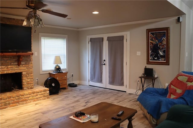 living room with a fireplace, light hardwood / wood-style floors, ceiling fan, and ornamental molding