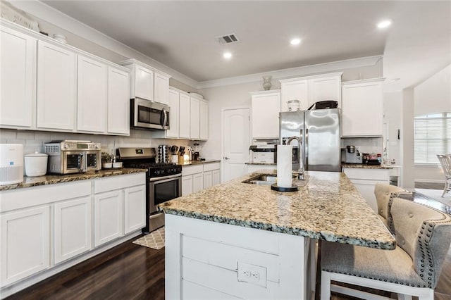 kitchen featuring stainless steel appliances, a kitchen island with sink, dark wood-type flooring, sink, and a breakfast bar area