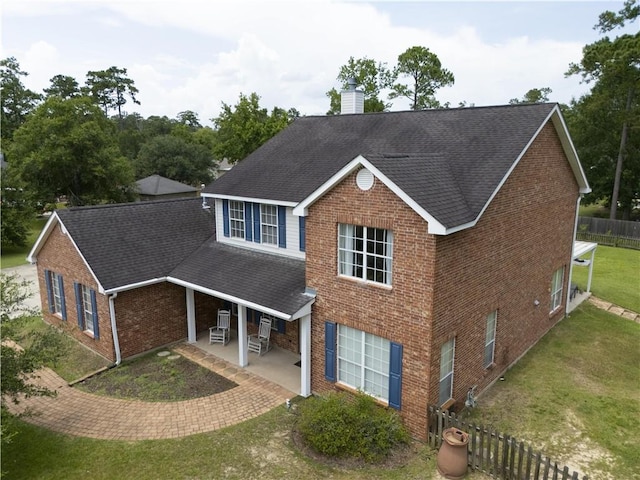 1024 Claire Dr, Slidell, LA 70461 - traditional-style house featuring brick siding, a shingled roof, a chimney, and a patio area