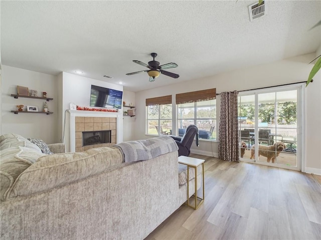 1024 Claire Dr, Slidell, LA 70461 - living room with light wood-type flooring, a tile fireplace, a ceiling fan, a textured ceiling, and recessed lighting