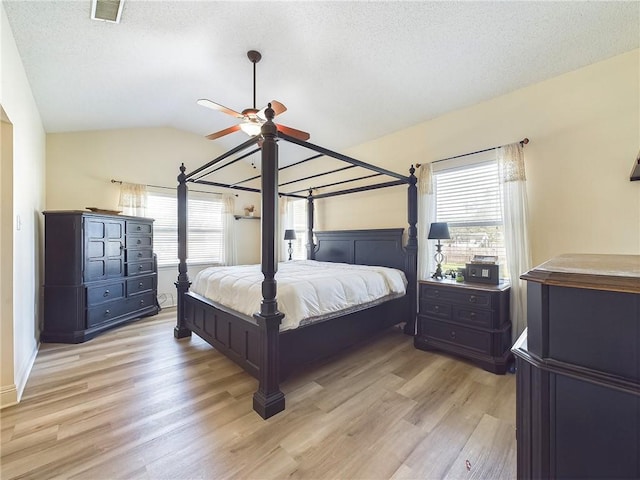 1024 Claire Dr, Slidell, LA 70461 - bedroom with light wood-style floors, lofted ceiling, multiple windows, a textured ceiling, and ceiling fan