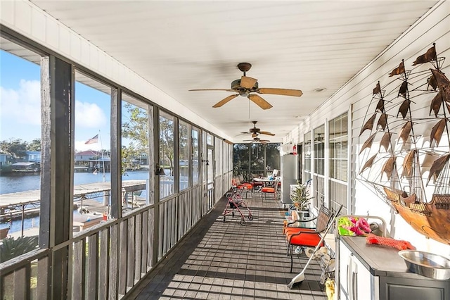 unfurnished sunroom with ceiling fan and a water view