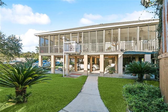 rear view of property with a patio, a lawn, and a sunroom