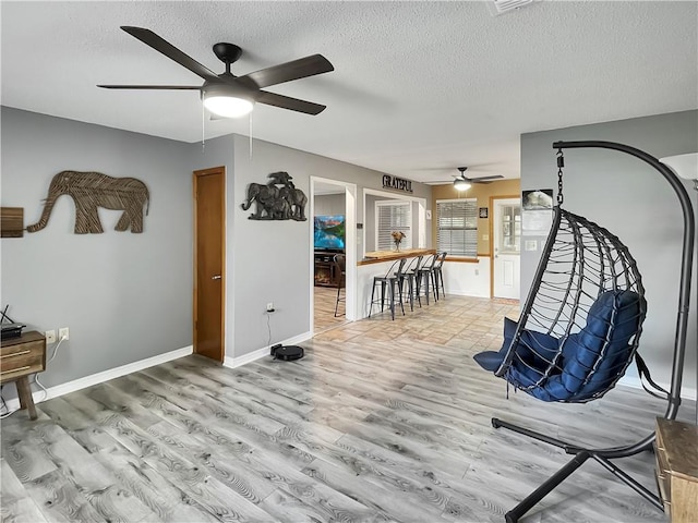 sitting room featuring a textured ceiling, light wood-type flooring, and ceiling fan