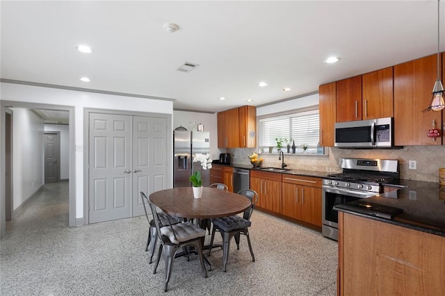 kitchen with backsplash, stainless steel appliances, hanging light fixtures, and sink