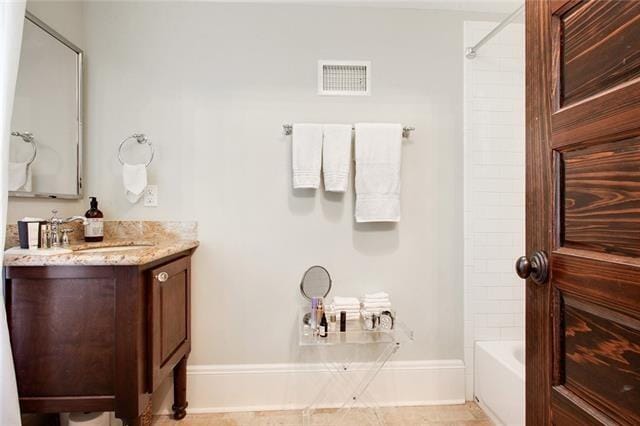 bathroom featuring tile patterned flooring, vanity, and tiled shower / bath combo