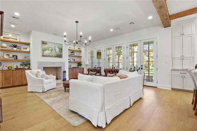 living room with beam ceiling, french doors, an inviting chandelier, a fireplace, and light wood-type flooring