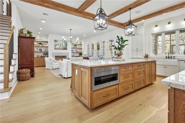 kitchen featuring white cabinetry, a center island, decorative light fixtures, and light hardwood / wood-style flooring