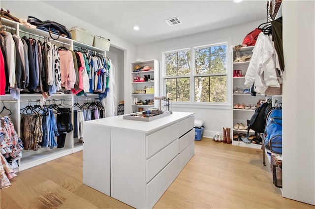 walk in closet with light hardwood / wood-style floors