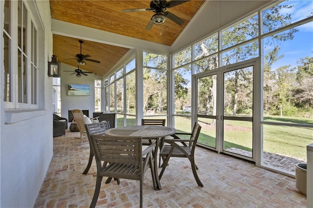 sunroom / solarium with vaulted ceiling, a healthy amount of sunlight, and wood ceiling