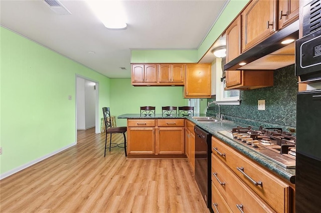 kitchen with a kitchen breakfast bar, sink, light hardwood / wood-style flooring, decorative backsplash, and stainless steel appliances