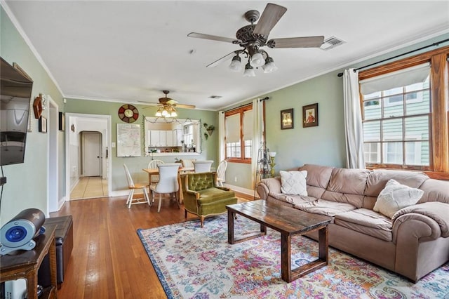 living room with ornamental molding, a healthy amount of sunlight, ceiling fan, and light wood-type flooring