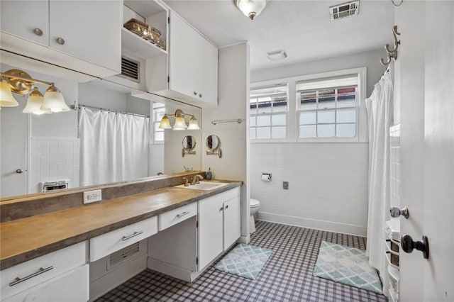 bathroom featuring tile patterned floors, vanity, toilet, and tile walls