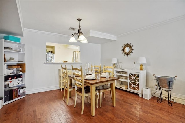 dining area with hardwood / wood-style flooring, crown molding, and a chandelier