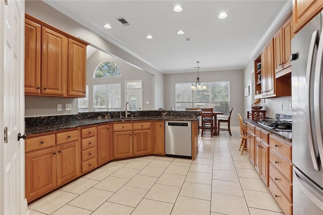 kitchen featuring sink, stainless steel appliances, kitchen peninsula, decorative light fixtures, and dark stone counters