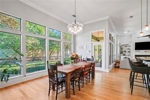 dining room with built in shelves, a wealth of natural light, and light hardwood / wood-style flooring