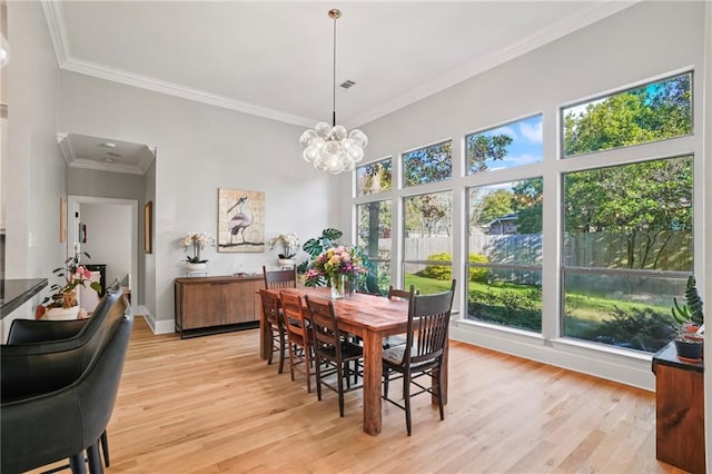 dining room with a healthy amount of sunlight, light hardwood / wood-style floors, and ornamental molding